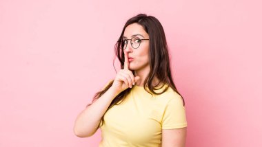 Genç ve güzel bir kadın sessizlik ve sessizlik istiyor, parmaklarıyla ağzının önünde işaret ediyor, 