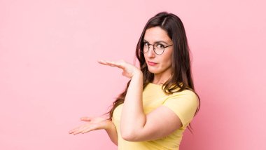 Genç ve güzel bir kadın bir objeyi iki eliyle fotokopi alanında tutuyor, bir objeyi gösteriyor, sunuyor ya da reklamını yapıyor.