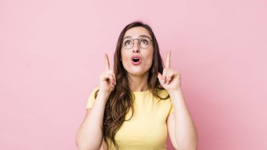 Genç ve güzel bir kadın huşu içinde ve ağzı açık bir şekilde şaşkın ve şaşkın bir bakışla yukarıya bakıyor.