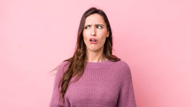 Genç, güzel bir kadın şaşkın, mutlu, şaşkın ve şaşırmış hissediyor, ağzı açık bir şekilde yana bakıyor.