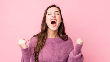 Genç ve güzel bir kadın öfkeli bir ifadeyle ya da yumruklarıyla başarıyı kutlarken agresif bir şekilde bağırıyor.