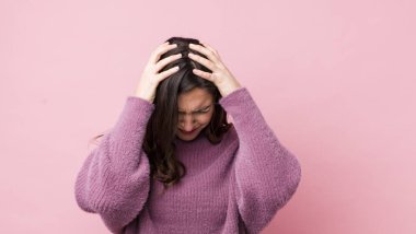 Genç ve güzel bir kadın stresli ve hayal kırıklığına uğramış hissediyor, elele tutuşuyor, yorgun, mutsuz ve migren ağrısı çekiyor.