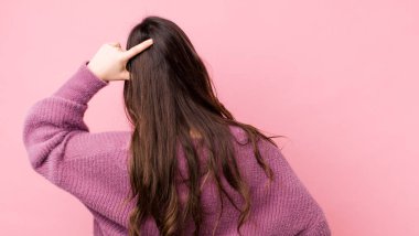 Genç, güzel bir kadın bilgisiz ve kafası karışık hissediyor, bir çözüm düşünüyor, eli kalçasında, diğeri kafasında, dikiz aynasından.