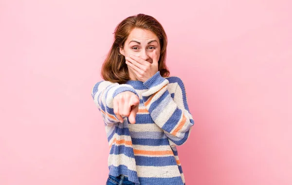 young pretty woman laughing at you, pointing to camera and making fun of or mocking you