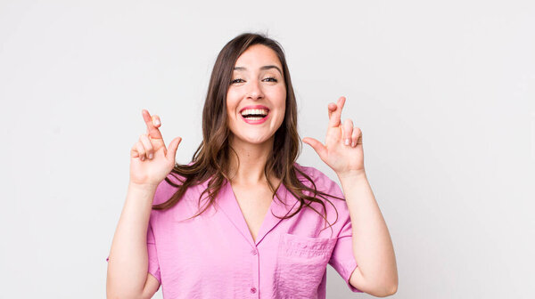 молодая красивая женщина улыбается и с тревогой скрещивает оба пальца, чувствуя беспокойство и желая или надеясь на удачу