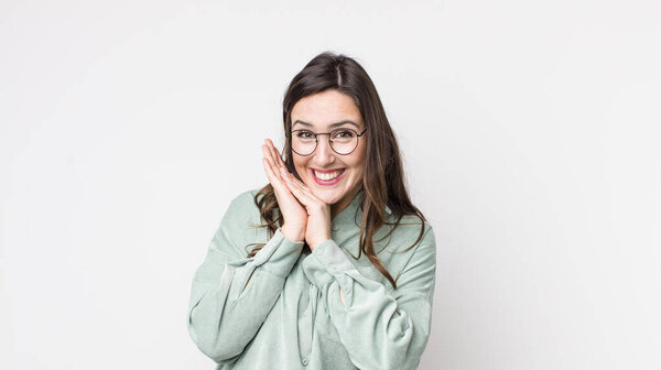 молодая красивая женщина чувствует себя в любви и выглядит мило, очаровательно и счастливо, улыбаясь романтически с руками рядом с лицом