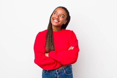 afro pretty woman feeling happy, proud and hopeful, wondering or thinking, looking up to copy space with crossed arms