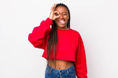 afro pretty woman smiling happily with funny face, joking and looking through peephole, spying on secrets