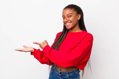 afro pretty woman smiling, feeling happy, carefree and satisfied, pointing to concept or idea on copy space on the side