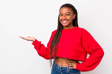 afro pretty woman smiling, feeling confident, successful and happy, showing concept or idea on copy space on the side
