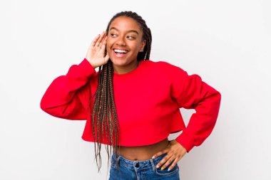 afro pretty woman smiling, looking curiously to the side, trying to listen to gossip or overhearing a secret