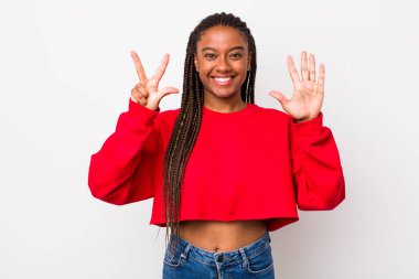 afro pretty woman smiling and looking friendly, showing number eight or eighth with hand forward, counting down
