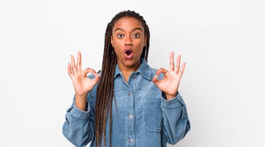 afro pretty woman feeling shocked, amazed and surprised, showing approval making okay sign with both hands