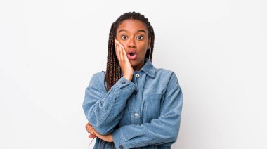 afro pretty woman feeling shocked and astonished holding face to hand in disbelief with mouth wide open