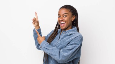 afro pretty woman feeling joyful and surprised, smiling with a shocked expression and pointing to the side