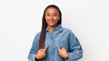 afro pretty woman pointing to self with a confused and quizzical look, shocked and surprised to be chosen
