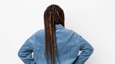 afro pretty woman feeling confused or full or doubts and questions, wondering, with hands on hips, rear view