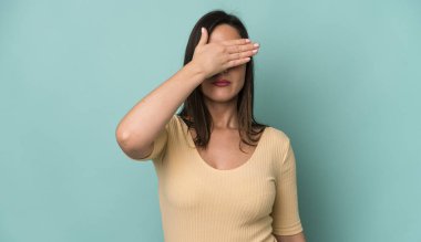 young adult pretty woman covering eyes with one hand feeling scared or anxious, wondering or blindly waiting for a surprise