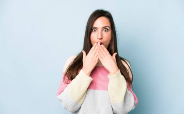 Genç ve güzel bir kadın endişeli, üzgün ve korkmuş hissediyor. Ağzını ellerle kapatıyor. Endişeli ve berbat görünüyor.