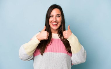 Genç ve güzel bir kadın gülümseyerek mutlu, pozitif, kendinden emin ve başarılı görünüyor.