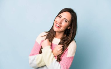 young adult pretty woman smiling cheerfully and celebrating, with fists clenched and arms crossed, feeling happy and positive