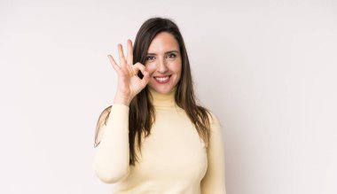 Genç ve güzel bir kadın mutlu, rahat ve tatmin olmuş hissediyor. Onayını iyi bir hareketle gösteriyor. Gülümsüyor.