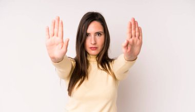 young adult pretty woman looking serious, unhappy, angry and displeased forbidding entry or saying stop with both open palms