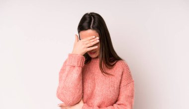 young adult pretty woman looking stressed, ashamed or upset, with a headache, covering face with hand
