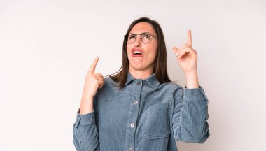 young adult pretty woman shrugging with a dumb, crazy, confused, puzzled expression, feeling annoyed and clueless