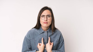 young adult pretty woman pointing to self with a confused and quizzical look, shocked and surprised to be chosen