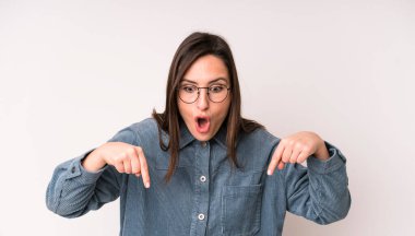 Genç, güzel bir kadın şoke olmuş, ağzı açık ve şaşkın bakıyor ve şaşkınlıkla onu işaret ediyor.