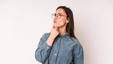 Genç ve güzel bir kadın düşünceli, meraklı ya da hayal kuruyor, hayal kuruyor ve mekanı kopyalamak için yukarı bakıyor.