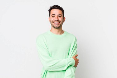 young handsome hicpanic man laughing shyly and cheerfully, with a friendly and positive but insecure attitude