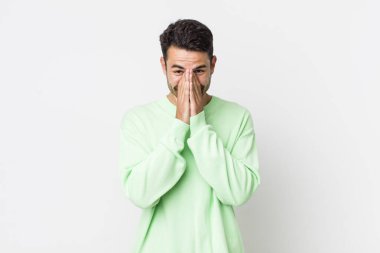 young handsome hicpanic man looking happy, cheerful, lucky and surprised covering mouth with both hands