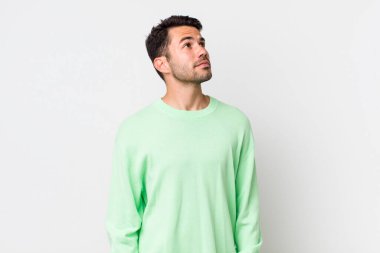 young handsome hicpanic man with a worried, confused, clueless expression, looking up to copy space, doubting