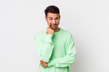 young handsome hicpanic man keeping an eye on you, not trusting, watching and staying alert and vigilant