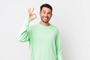 young handsome hicpanic man feeling happy, relaxed and satisfied, showing approval with okay gesture, smiling