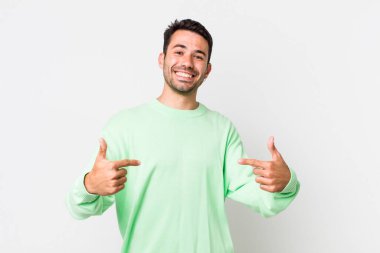 young handsome hicpanic man looking proud, arrogant, happy, surprised and satisfied, pointing to self, feeling like a winner