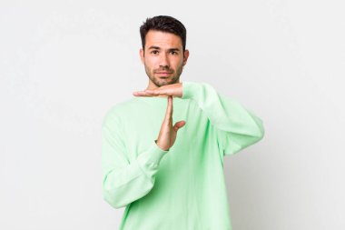 young handsome hicpanic man looking serious, stern, angry and displeased, making time out sign