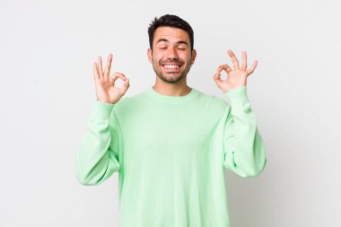 young handsome hicpanic man looking concentrated and meditating, feeling satisfied and relaxed, thinking or making a choice