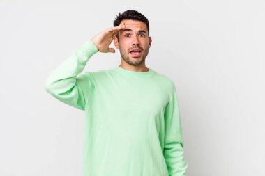 young handsome hicpanic man looking happy, astonished and surprised, smiling and realizing amazing and incredible good news