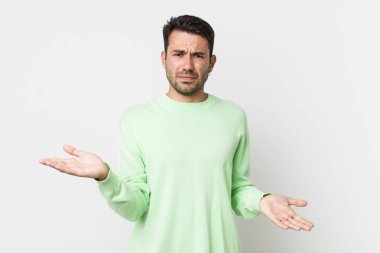 young handsome hicpanic man looking puzzled, confused and stressed, wondering between different options, feeling uncertain