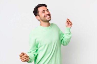 young handsome hicpanic man smiling, feeling carefree, relaxed and happy, dancing and listening to music, having fun at a party