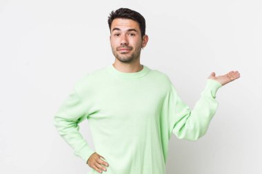 young handsome hicpanic man smiling, feeling confident, successful and happy, showing concept or idea on copy space on the side