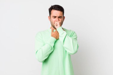 young handsome hicpanic man feeling ill with a sore throat and flu symptoms, coughing with mouth covered