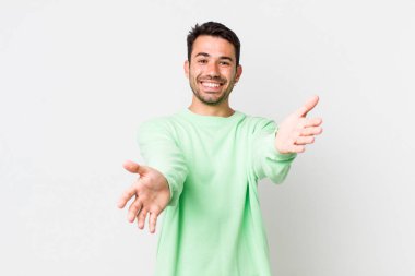 young handsome hicpanic man smiling cheerfully giving a warm, friendly, loving welcome hug, feeling happy and adorable