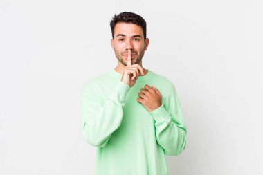 young handsome hicpanic man looking serious and cross with finger pressed to lips demanding silence or quiet, keeping a secret