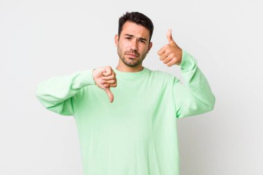 young handsome hicpanic man feeling confused, clueless and unsure, weighting the good and bad in different options or choices