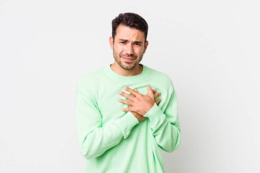 young handsome hicpanic man looking sad, hurt and heartbroken, holding both hands close to heart, crying and feeling depressed