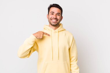 young handsome hicpanic man looking happy, proud and surprised, cheerfully pointing to self, feeling confident and lofty
